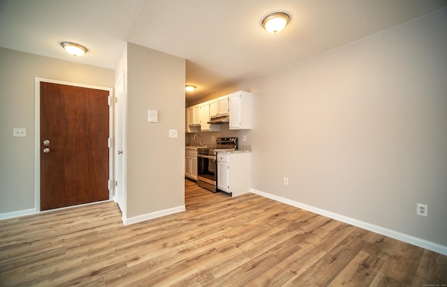 kitchen featuring electric stove, sink, white cabinetry, and light wood-type flooring