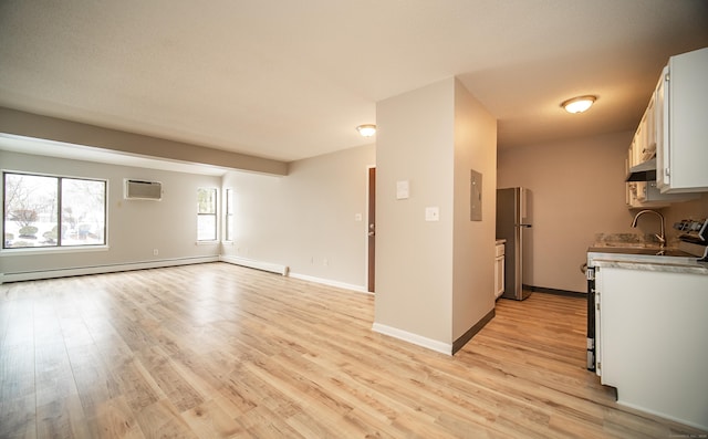 unfurnished living room with a baseboard radiator, an AC wall unit, and light wood-type flooring