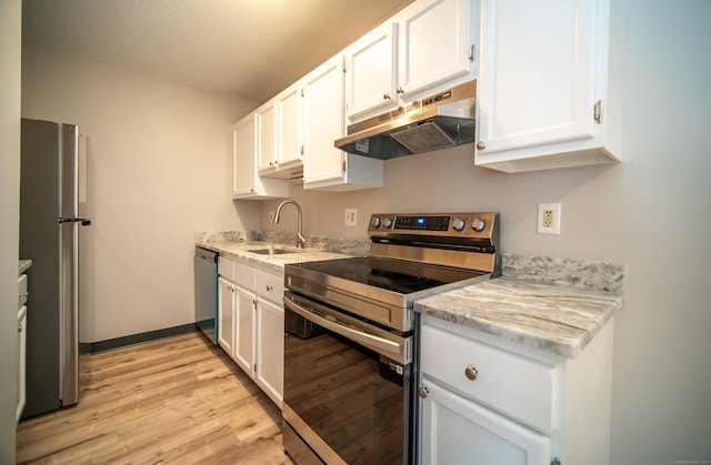 kitchen featuring sink, appliances with stainless steel finishes, light stone counters, light hardwood / wood-style floors, and white cabinets