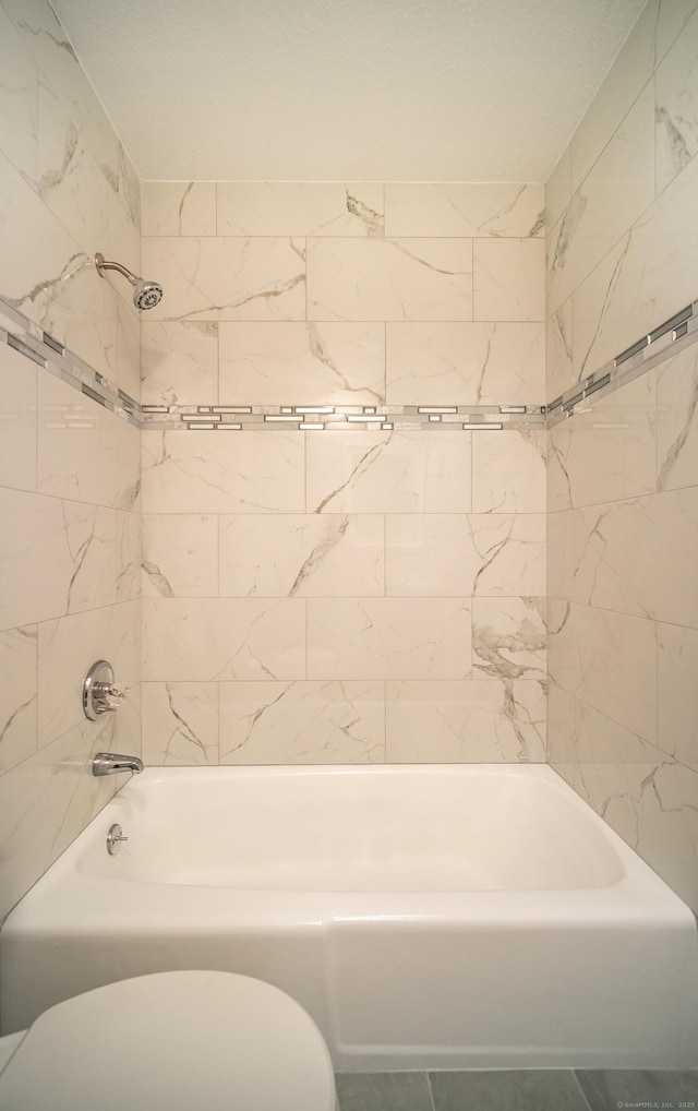 bathroom with tiled shower / bath and toilet