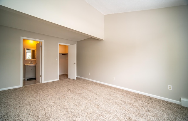 unfurnished bedroom featuring a closet, carpet floors, ensuite bath, and a spacious closet