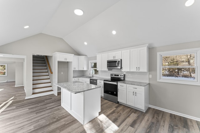 kitchen with white cabinetry, light stone countertops, appliances with stainless steel finishes, and a kitchen island