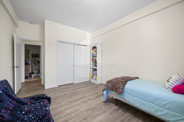 bedroom with light hardwood / wood-style floors and a closet