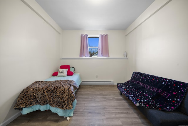 bedroom with a baseboard heating unit and light wood-type flooring