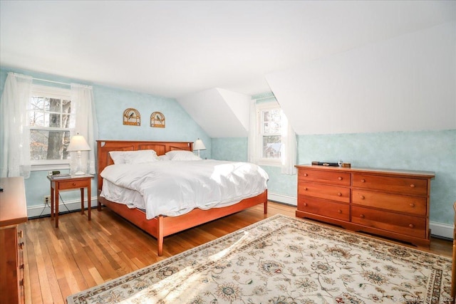 bedroom featuring a baseboard radiator, lofted ceiling, and hardwood / wood-style floors