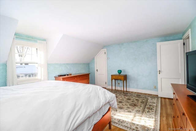 bedroom featuring lofted ceiling and light wood-type flooring