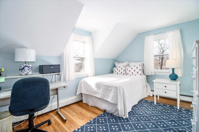 bedroom with dark hardwood / wood-style floors, vaulted ceiling, and a baseboard heating unit