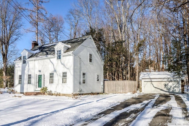 snow covered property with a garage and an outdoor structure