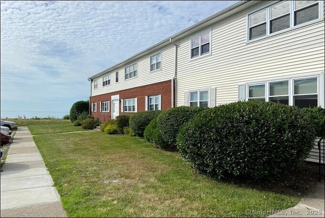 view of side of property featuring a yard and brick siding