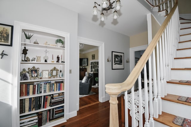 stairway with wood-type flooring and a chandelier