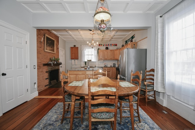 dining space featuring an inviting chandelier, brick wall, coffered ceiling, and dark hardwood / wood-style flooring