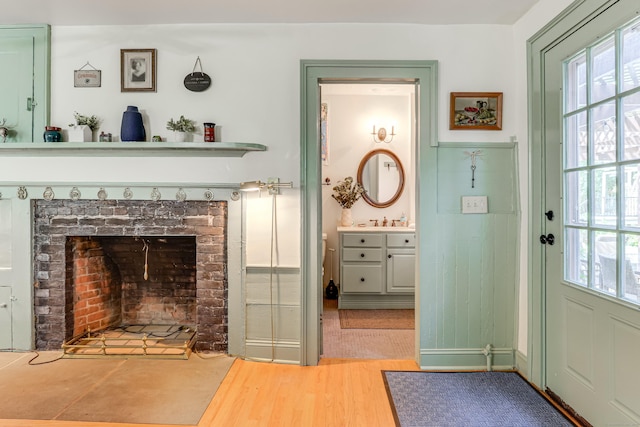 interior space featuring a brick fireplace, light hardwood / wood-style flooring, and a healthy amount of sunlight