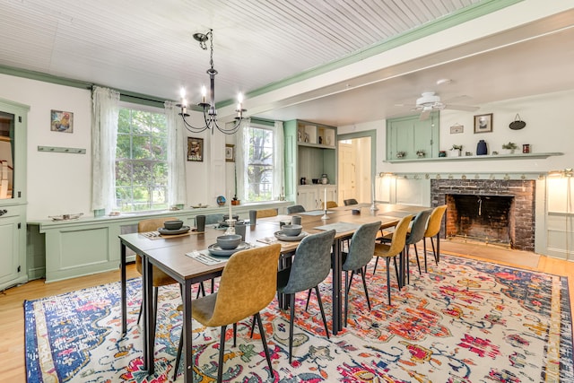 dining space featuring ceiling fan with notable chandelier, beamed ceiling, and light wood-type flooring