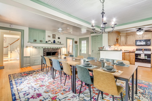 dining room with ceiling fan, a fireplace, and light hardwood / wood-style floors