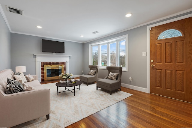 living room featuring hardwood / wood-style floors, a fireplace, and ornamental molding