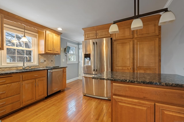 kitchen with tasteful backsplash, appliances with stainless steel finishes, sink, and pendant lighting