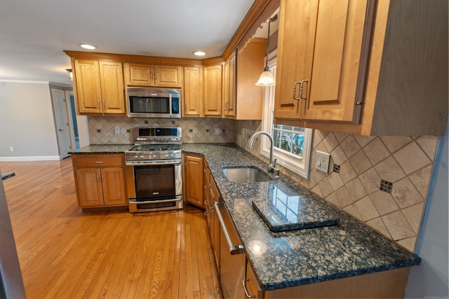 kitchen featuring stainless steel appliances, hanging light fixtures, sink, and dark stone countertops