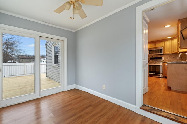 interior space featuring crown molding, ceiling fan, sink, and light wood-type flooring