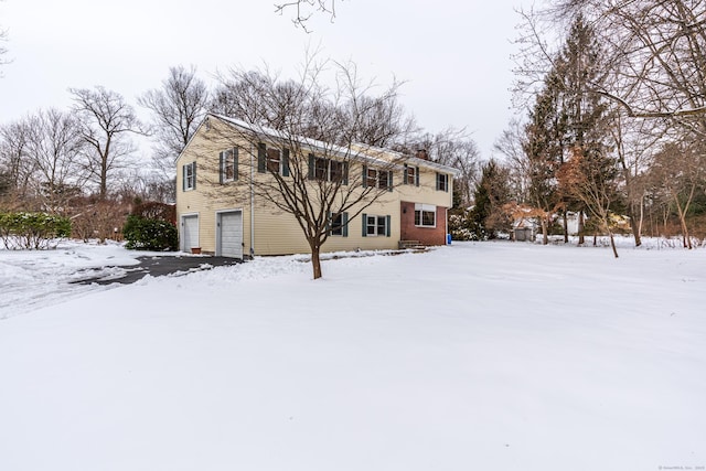 snow covered house featuring a garage