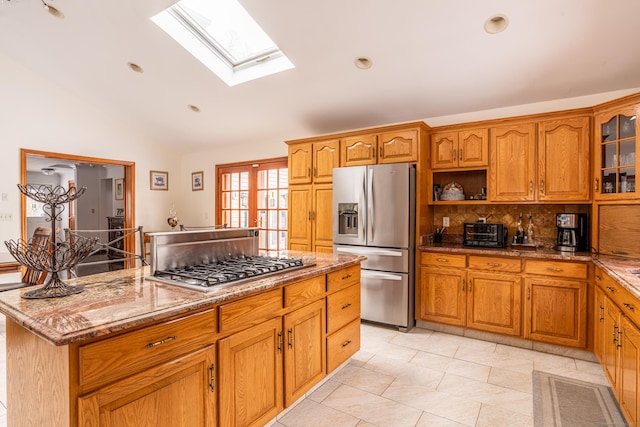 kitchen with a kitchen island, lofted ceiling, decorative backsplash, stainless steel appliances, and light stone countertops