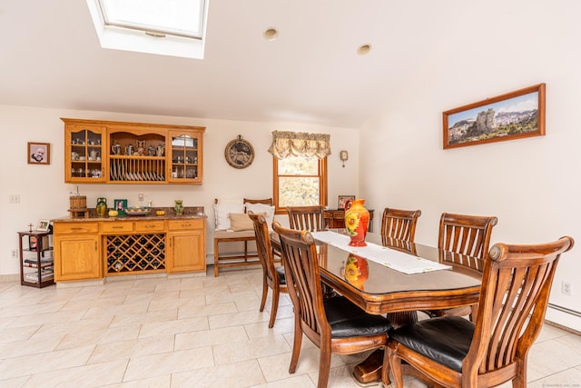 tiled dining area featuring a baseboard radiator and vaulted ceiling