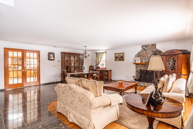 living room featuring a notable chandelier, a fireplace, ornamental molding, and french doors