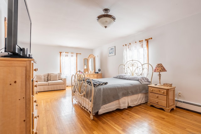 bedroom with light hardwood / wood-style flooring and a baseboard heating unit