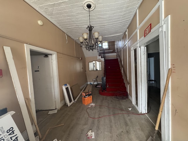 hallway featuring stairway, wood finished floors, and an inviting chandelier