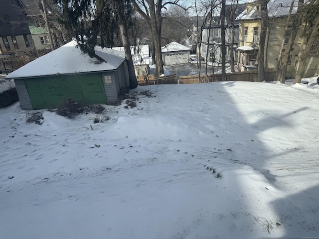 yard covered in snow featuring a garage and an outbuilding