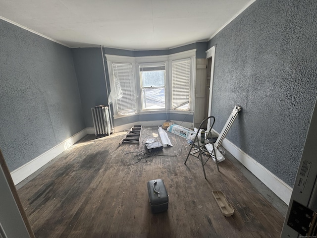 empty room featuring a textured wall, crown molding, dark wood finished floors, and baseboards