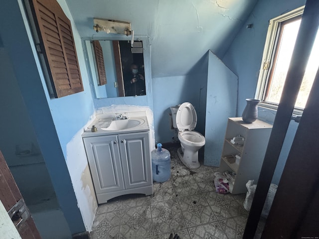 bathroom with toilet, vaulted ceiling, and vanity