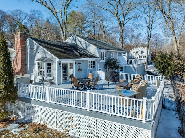 snow covered back of property featuring a wooden deck