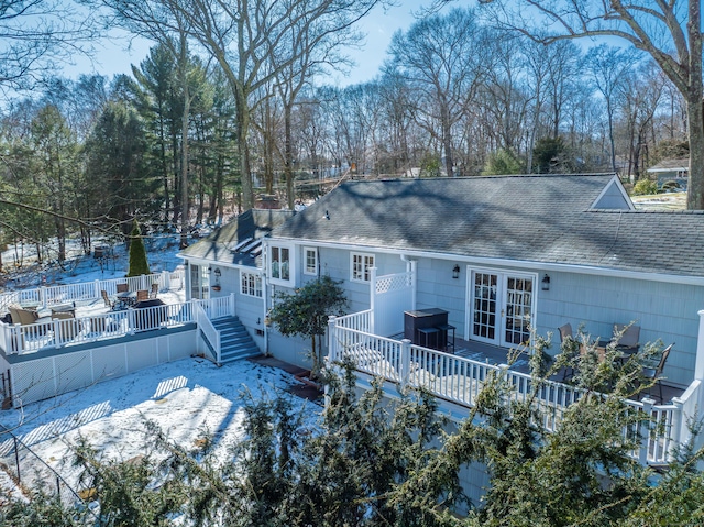 snow covered house featuring french doors and a deck