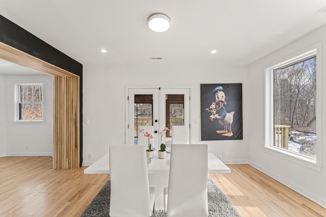 dining space with light hardwood / wood-style flooring, plenty of natural light, and french doors