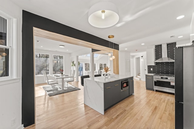 765 Durham Rd, Guilford, CT 06437 - kitchen featuring modern cabinets, wall chimney range hood, appliances with stainless steel finishes, light wood finished floors, and backsplash