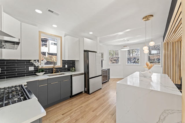 kitchen featuring sink, fridge, dishwasher, pendant lighting, and white cabinets