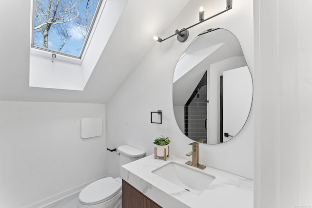 bathroom featuring vanity, lofted ceiling with skylight, and toilet