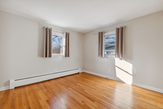 spare room featuring hardwood / wood-style flooring, plenty of natural light, and baseboard heating