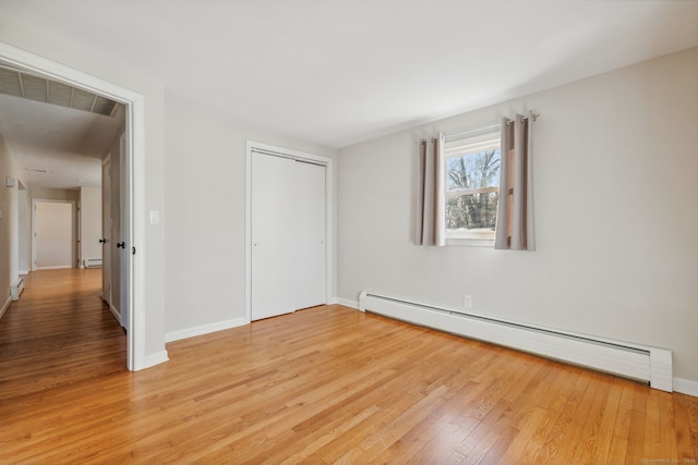 unfurnished bedroom featuring a baseboard radiator, a closet, and light hardwood / wood-style flooring