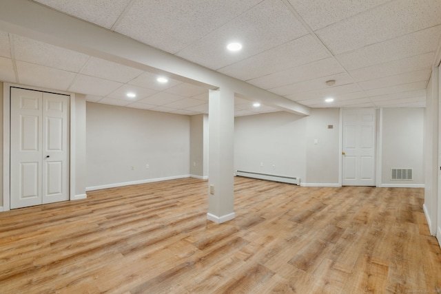 basement featuring light wood-type flooring and baseboard heating