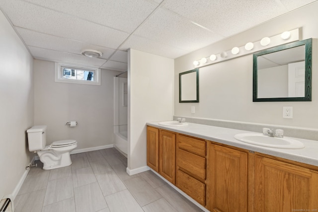 full bathroom featuring toilet, a drop ceiling, vanity, shower / washtub combination, and a baseboard heating unit