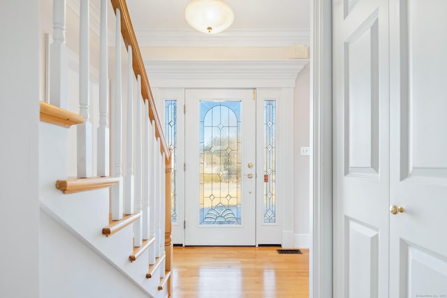 foyer entrance with crown molding and light hardwood / wood-style floors