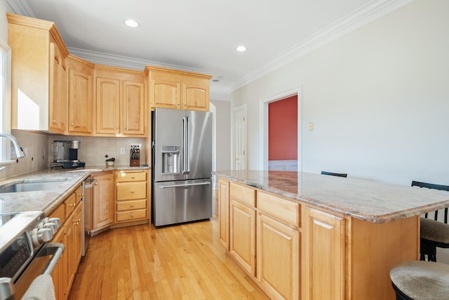 kitchen featuring a breakfast bar, light brown cabinetry, sink, a center island, and stainless steel appliances