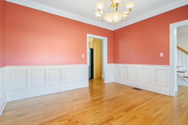 unfurnished room with a notable chandelier, crown molding, and light hardwood / wood-style flooring