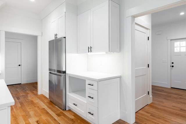 kitchen with white cabinetry, light hardwood / wood-style floors, and stainless steel refrigerator