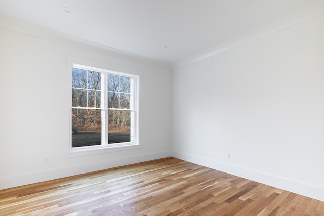 empty room with crown molding and light hardwood / wood-style floors