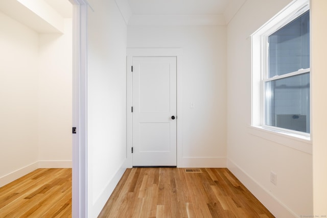 hallway with light hardwood / wood-style flooring and ornamental molding