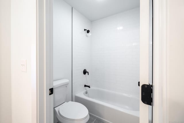 bathroom featuring tiled shower / bath combo and toilet