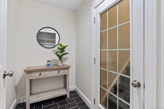 doorway with dark tile patterned floors and baseboards