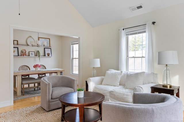 living room with lofted ceiling, light wood finished floors, baseboards, and visible vents